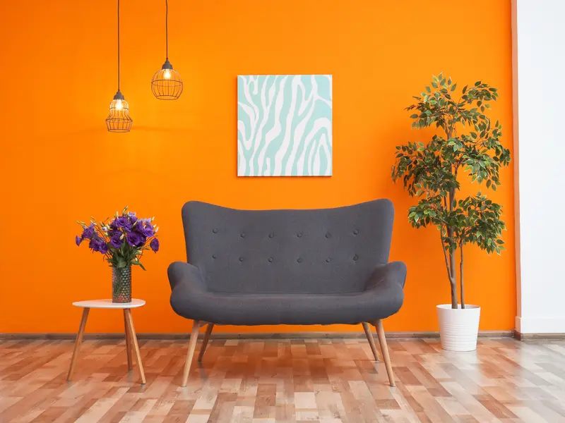 Salón moderno con pared naranja pintada por profesionales de pintura interior en Lleida